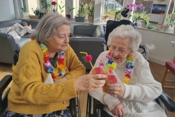 Two customers at Kippingtons Care Home clinking their drinks together in celebration