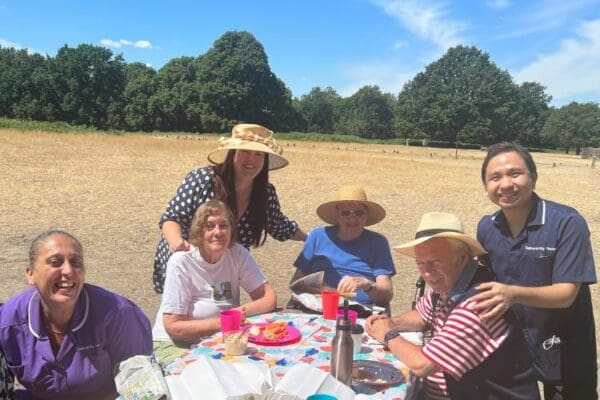 Galsworthy House Care Home Residents around a picnic table in the park enjoying the blue skies and sun