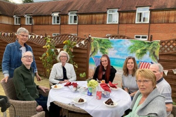 Six Dormy House Care Home residents and loved ones around a round table enjoying each-others company 