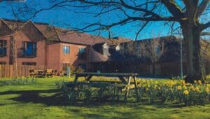 An exterior photograph of Abbeycrest Nursing Home with a picnic bench