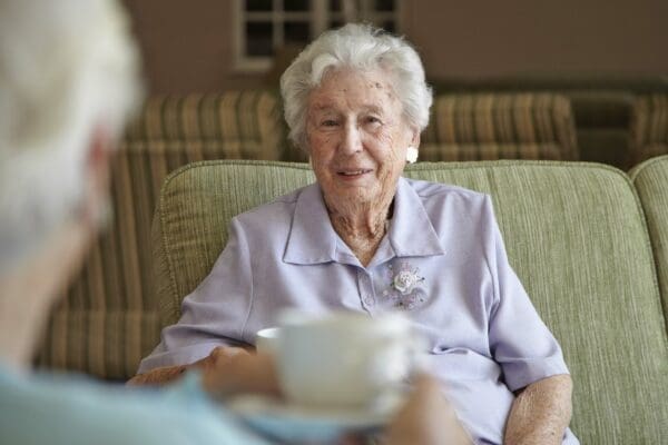 Elderly women, aged 80-85, talking and drinking tea together in a private retirement home