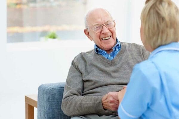 Senior man holding nurses hand while smiling