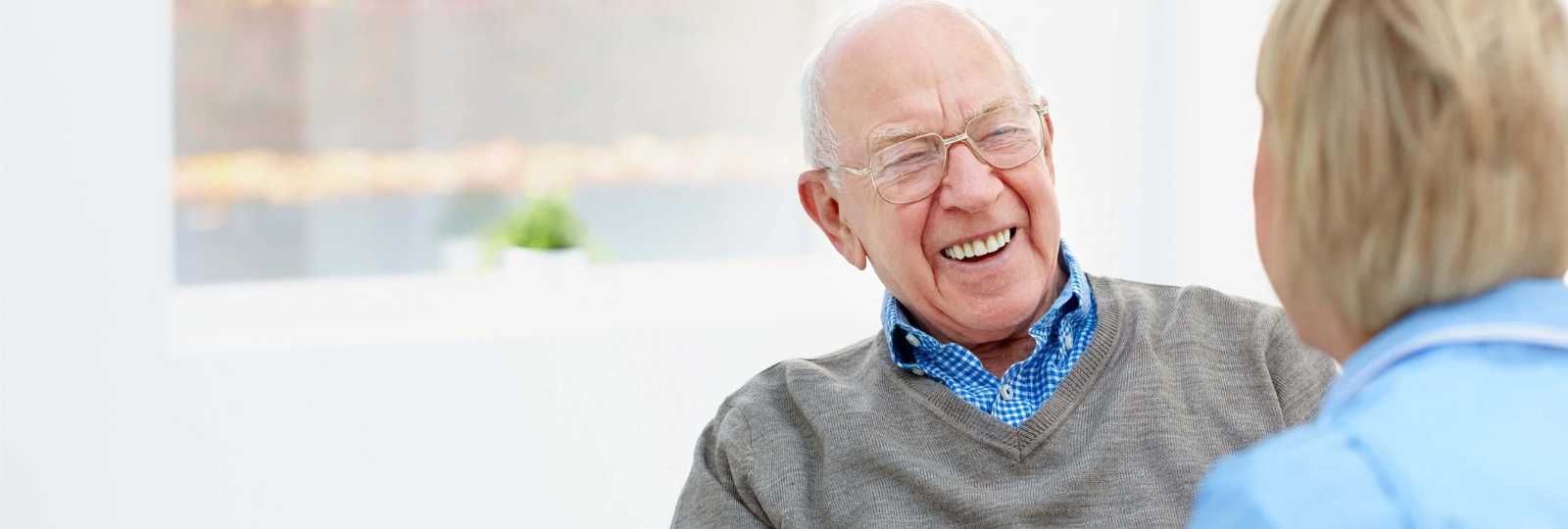 Senior man smiling while in conversation with a nurse