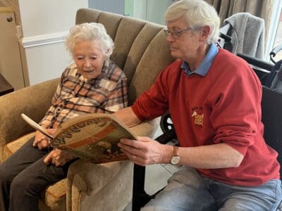 Female resident looking at and discussing literature with Jersey Heritage staff, L'Hermitage reminiscence session